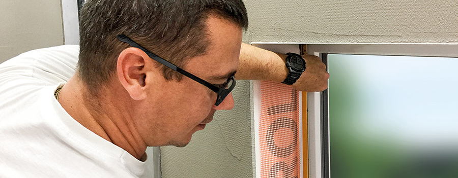 Mann klebt beim Händler-Seminar ein Fenster sorgfältig mit orangem Klebeband ab.